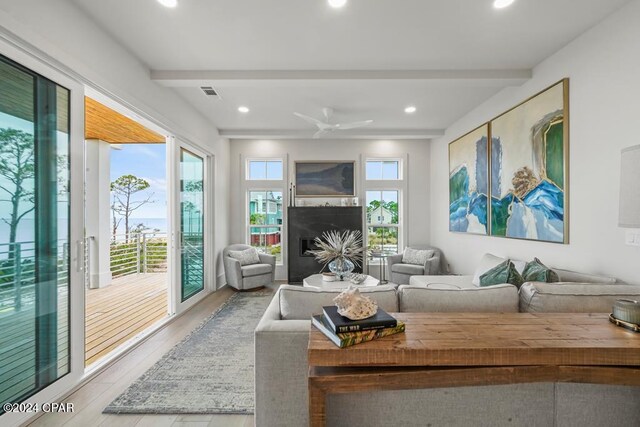 living room with ceiling fan, beamed ceiling, and light wood-type flooring