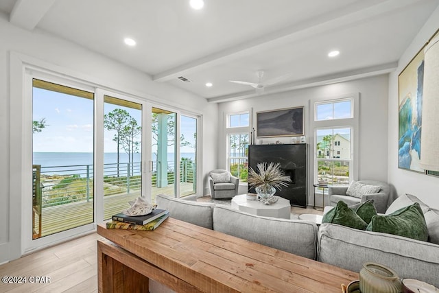 sunroom with beam ceiling, a water view, plenty of natural light, and ceiling fan