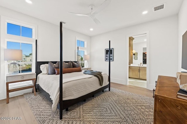 bedroom featuring ceiling fan, ensuite bath, sink, and light hardwood / wood-style flooring