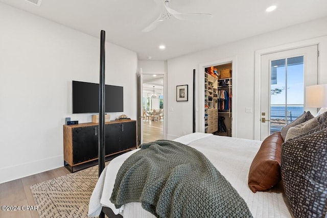 bedroom with a walk in closet, access to outside, ceiling fan, hardwood / wood-style floors, and a closet