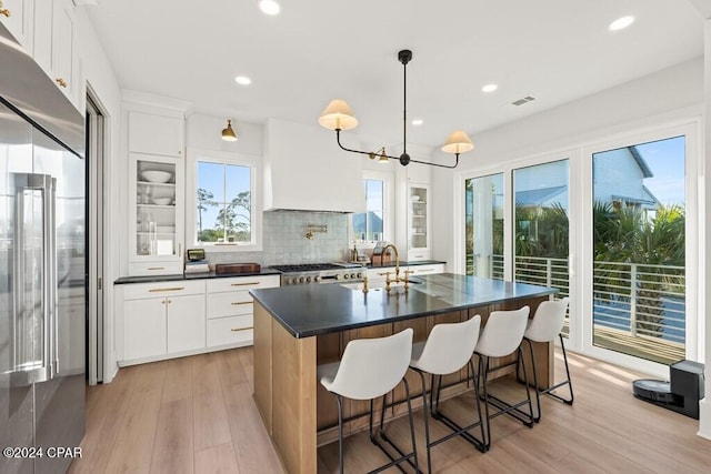 kitchen with a center island with sink, white cabinets, light wood-type flooring, and appliances with stainless steel finishes