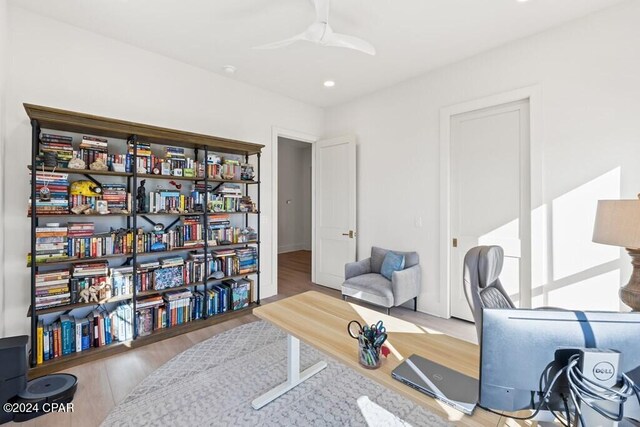 living area featuring hardwood / wood-style floors and ceiling fan