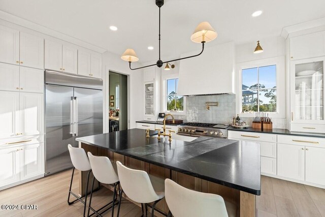 kitchen featuring a wealth of natural light, a kitchen island with sink, and stainless steel built in fridge