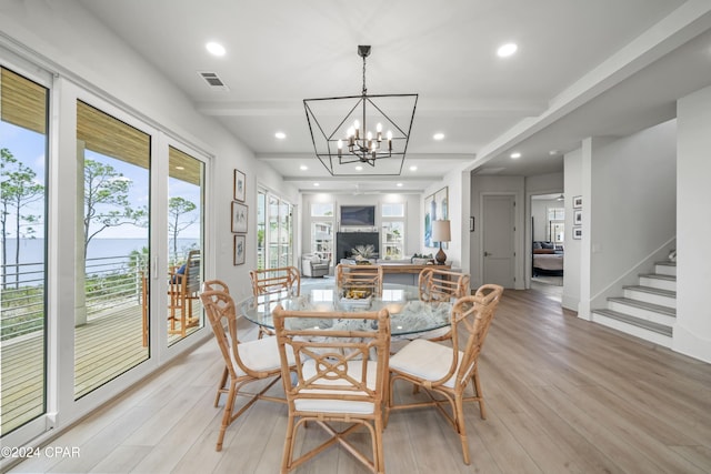 dining area with light hardwood / wood-style floors, a wealth of natural light, and a chandelier