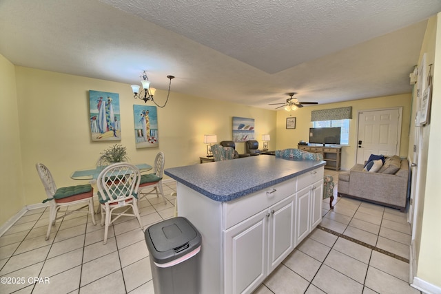 kitchen featuring white cabinetry, a center island, a textured ceiling, light tile patterned floors, and ceiling fan with notable chandelier