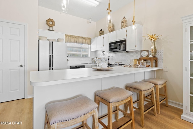 kitchen featuring tasteful backsplash, kitchen peninsula, pendant lighting, white cabinets, and black appliances