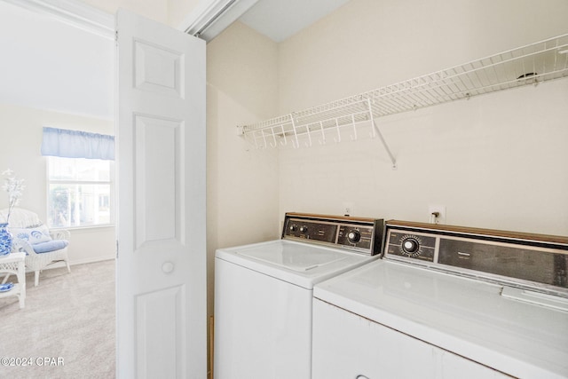 laundry room with washer and dryer and light colored carpet