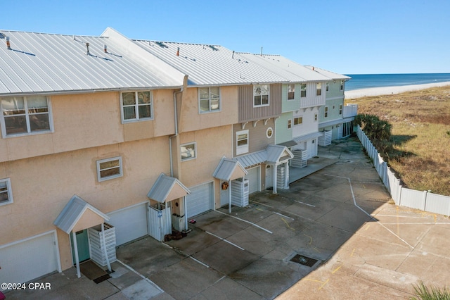 view of building exterior featuring a water view and a beach view