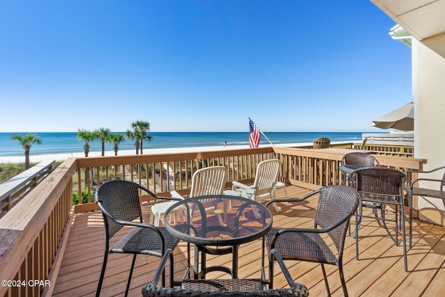 wooden terrace featuring a beach view and a water view