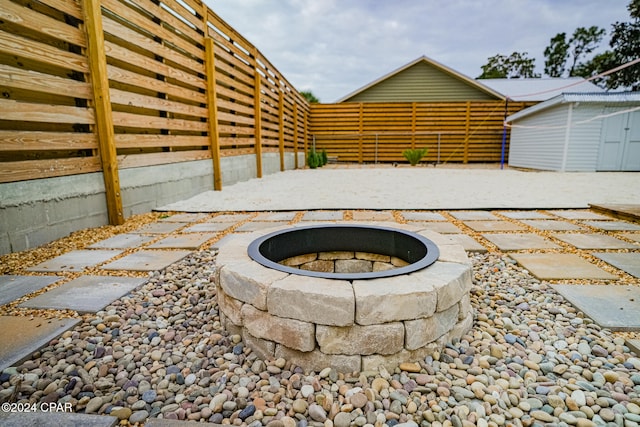 view of patio with a storage unit and an outdoor fire pit