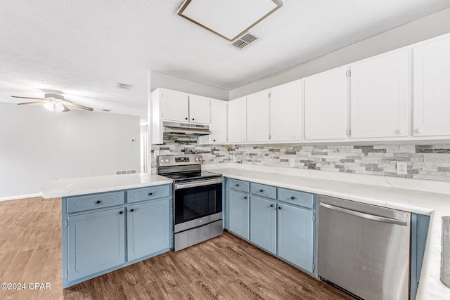 kitchen featuring blue cabinets, light hardwood / wood-style flooring, tasteful backsplash, white cabinetry, and stainless steel appliances