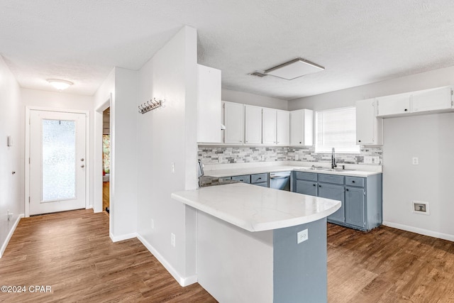 kitchen with hardwood / wood-style floors, kitchen peninsula, decorative backsplash, a textured ceiling, and white cabinetry