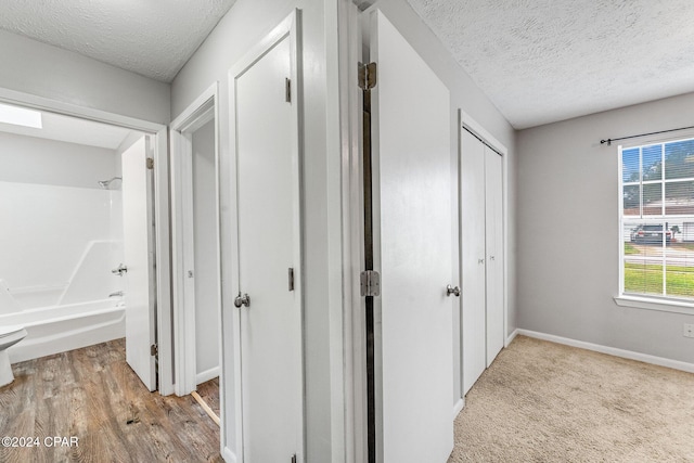 hall featuring light hardwood / wood-style floors and a textured ceiling