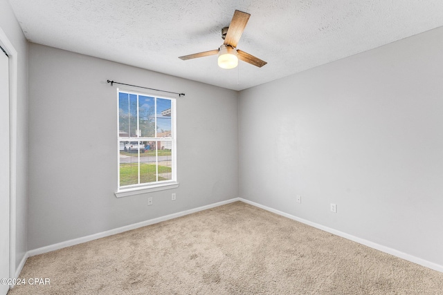 carpeted spare room featuring a textured ceiling and ceiling fan