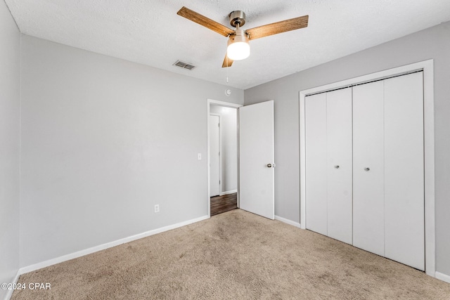 unfurnished bedroom featuring light carpet, a textured ceiling, a closet, and ceiling fan