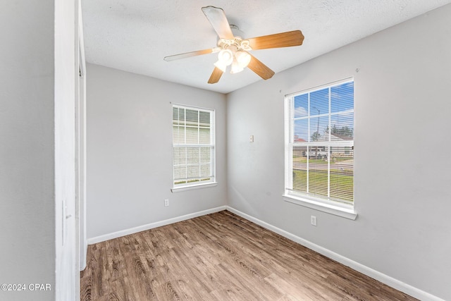 spare room with a textured ceiling, light hardwood / wood-style floors, and ceiling fan