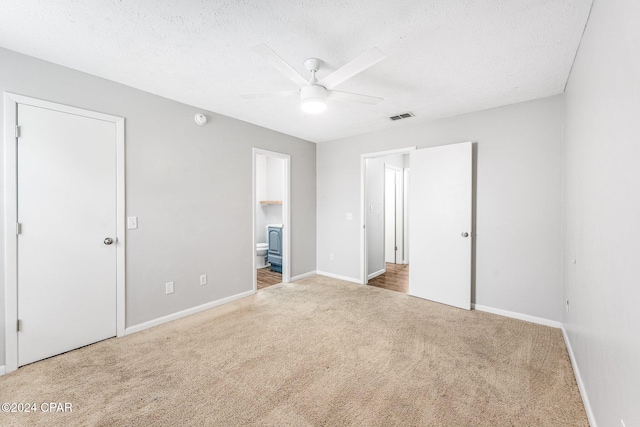 unfurnished bedroom with carpet flooring, ceiling fan, a textured ceiling, and connected bathroom