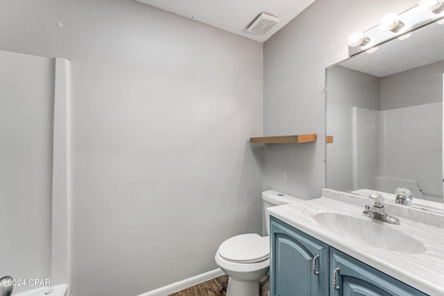 bathroom featuring a textured ceiling, vanity, a shower, hardwood / wood-style flooring, and toilet