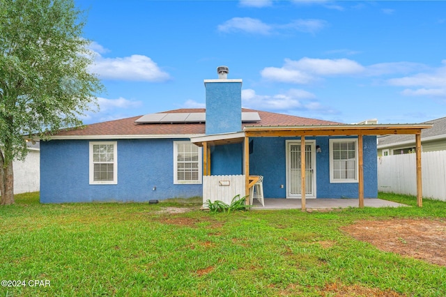 back of property featuring a lawn, solar panels, and a patio