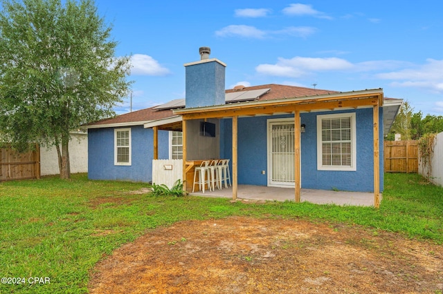 rear view of property with a lawn, solar panels, and a patio