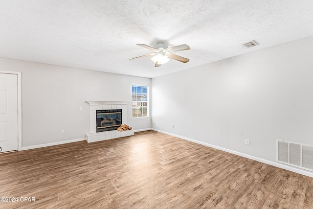 unfurnished living room featuring a fireplace, ceiling fan, hardwood / wood-style floors, and a textured ceiling