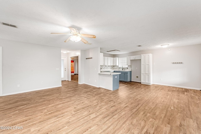 unfurnished living room with ceiling fan, light hardwood / wood-style floors, sink, and a textured ceiling