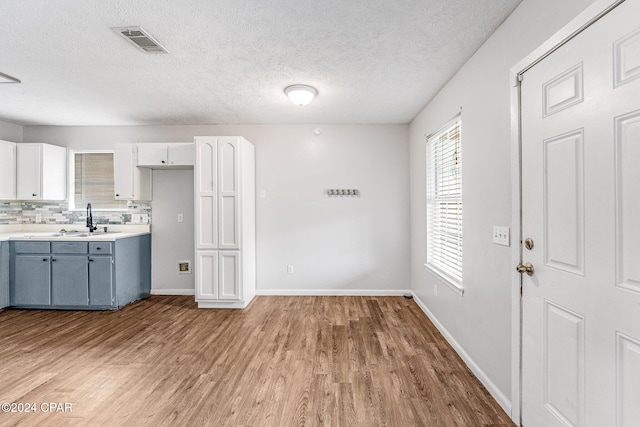 kitchen featuring tasteful backsplash, gray cabinetry, light hardwood / wood-style flooring, and white cabinets