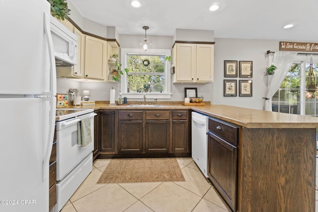 kitchen featuring kitchen peninsula, cream cabinets, pendant lighting, and white appliances