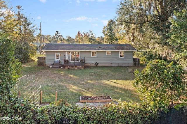 rear view of house featuring a lawn and a deck