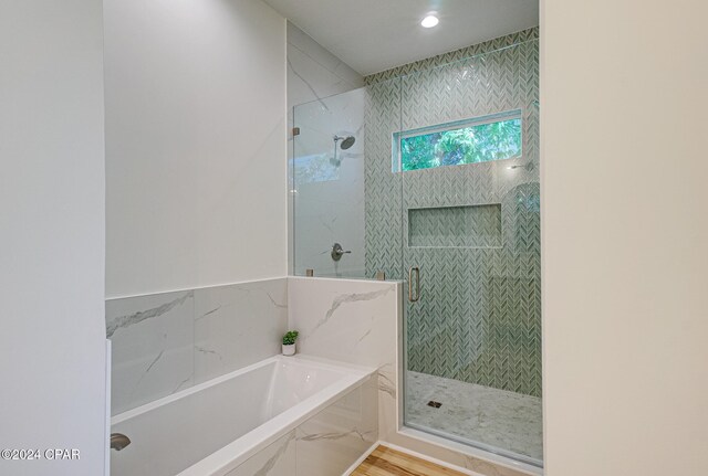 bathroom with hardwood / wood-style flooring and shower with separate bathtub