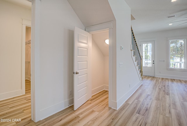 foyer entrance with ceiling fan, vaulted ceiling, and light wood-type flooring