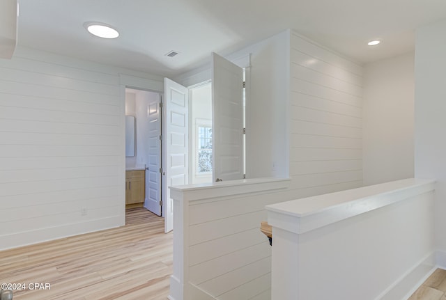 hallway featuring light hardwood / wood-style flooring and wooden walls