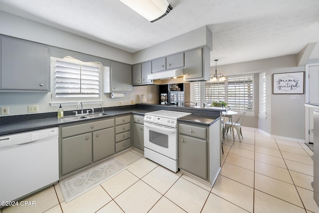 kitchen with white appliances, sink, hanging light fixtures, a textured ceiling, and kitchen peninsula