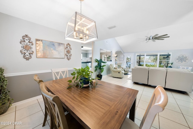 tiled dining room with ceiling fan with notable chandelier and vaulted ceiling