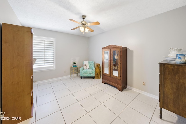 living area featuring ceiling fan, light tile patterned floors, and a textured ceiling