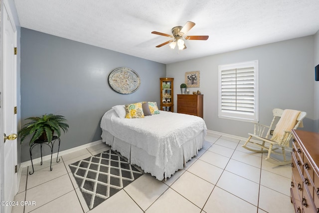 bedroom featuring ceiling fan, light tile patterned flooring, and a textured ceiling