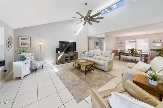 living room with ceiling fan with notable chandelier, high vaulted ceiling, and light tile patterned flooring