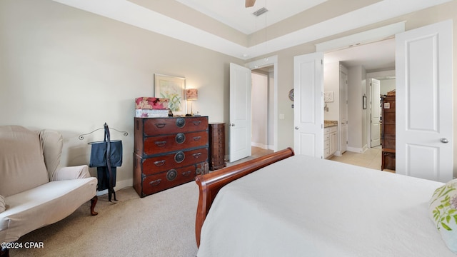 bedroom with ceiling fan, ensuite bathroom, and light carpet