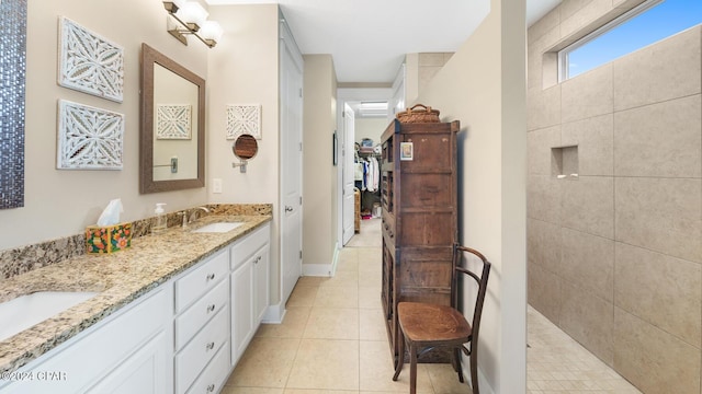 full bathroom featuring double vanity, a sink, tile patterned flooring, baseboards, and walk in shower