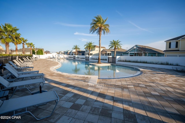 community pool with a patio area, a residential view, and fence