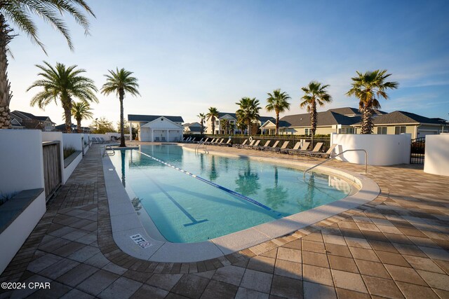 pool featuring a patio area, a residential view, fence, and an outbuilding