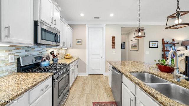 kitchen with white cabinets, decorative light fixtures, sink, and appliances with stainless steel finishes