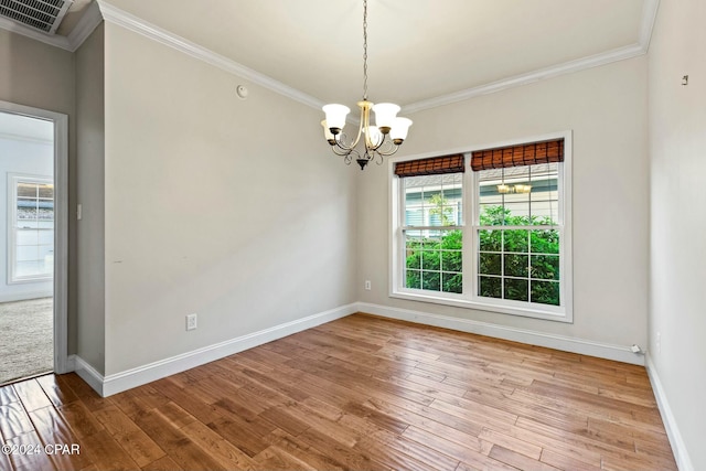 empty room with crown molding, a chandelier, and hardwood / wood-style flooring