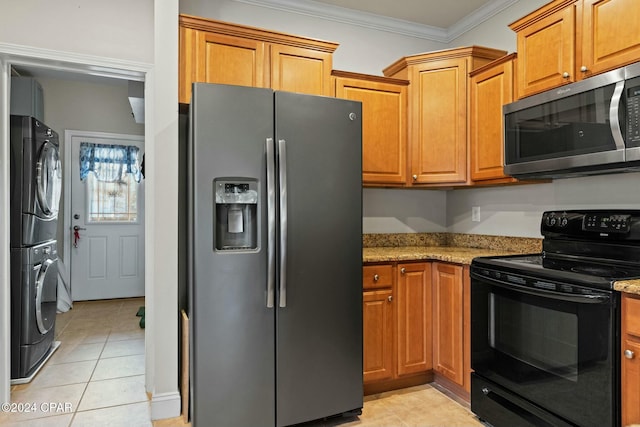 kitchen featuring stacked washer and dryer, light tile patterned floors, ornamental molding, appliances with stainless steel finishes, and light stone counters