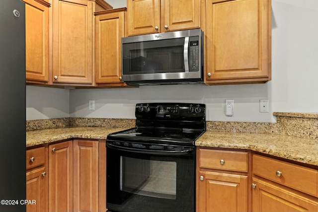 kitchen with light stone countertops and black appliances