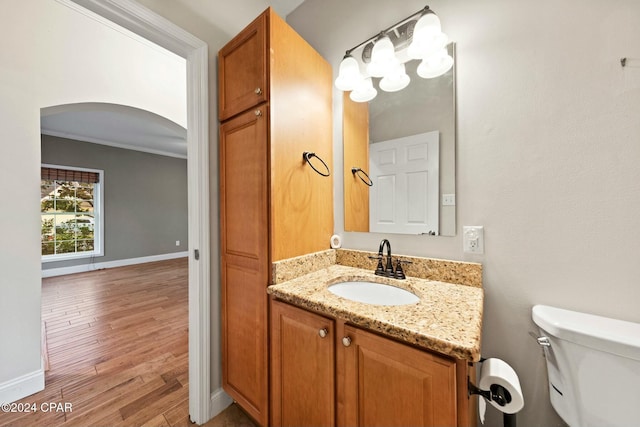 bathroom featuring hardwood / wood-style flooring, vanity, toilet, and ornamental molding