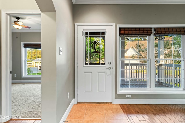 tiled entryway with ceiling fan and ornamental molding