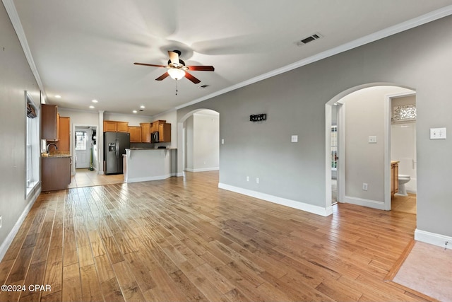 unfurnished living room with ceiling fan, light hardwood / wood-style flooring, sink, and ornamental molding