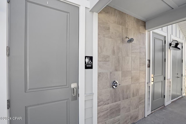 bathroom with tiled shower and concrete floors