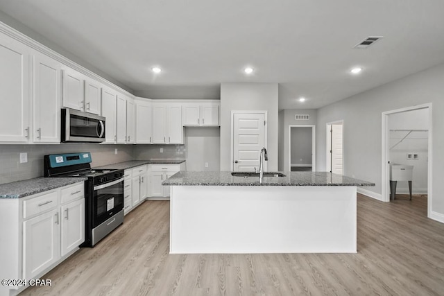 kitchen featuring sink, white cabinetry, dark stone countertops, appliances with stainless steel finishes, and a kitchen island with sink